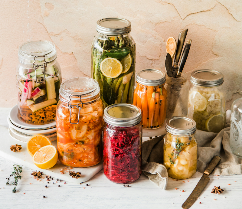 A variety of jars with picklesinlcuding carrots, bettropt, cucumber, lemons and onions.